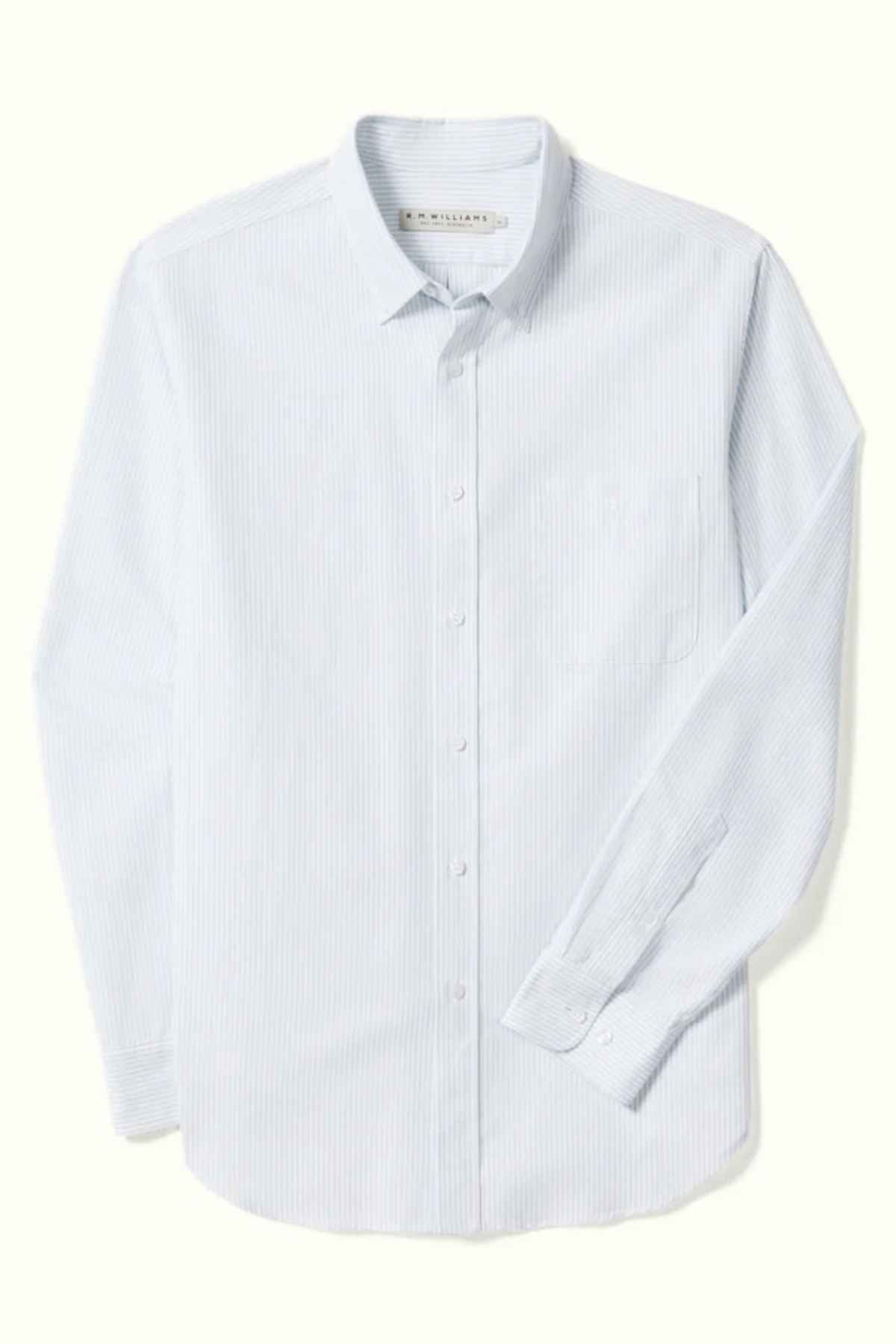 The RM Williams Regular Shirt is a light blue, long-sleeve dress shirt adorned with a subtle vertical stripe pattern. Crafted from striped oxford cotton, it features a button-down front and a pocket on the left side. This shirt also boasts a classic collar and buttoned cuffs, designed in a slimmer cut that stands out against the plain white background.