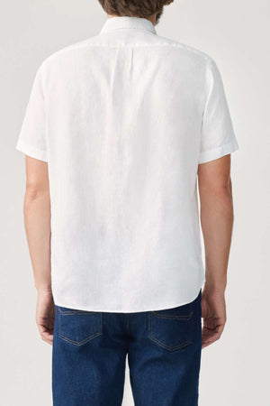 A person wearing an RM Williams Regular Short Sleeve Shirt in organic cotton, paired with blue jeans, is viewed from behind against a neutral background.