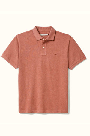 The RM Williams Rod Polo is a rust-colored classic fit shirt with short sleeves and a collar, made from soft organic cotton. It includes two buttons and features a small logo on the left chest, elegantly contrasting against a light background.