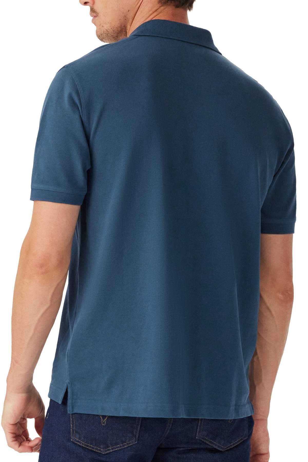 A man is shown from the back wearing the RM Williams Rod Polo, a short-sleeved blue shirt, paired with dark jeans.