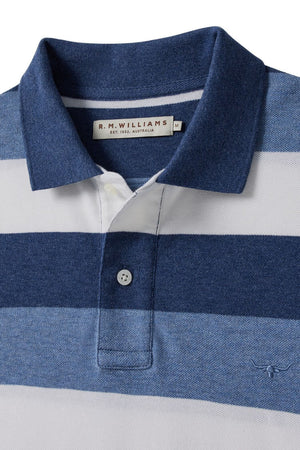 A close-up of the RM Williams Rod Polo, made from cotton pique with navy, white, and light blue stripes. Features a collar, two-button placket, R.M. Williams label inside the collar, and signature longhorn embroidery.