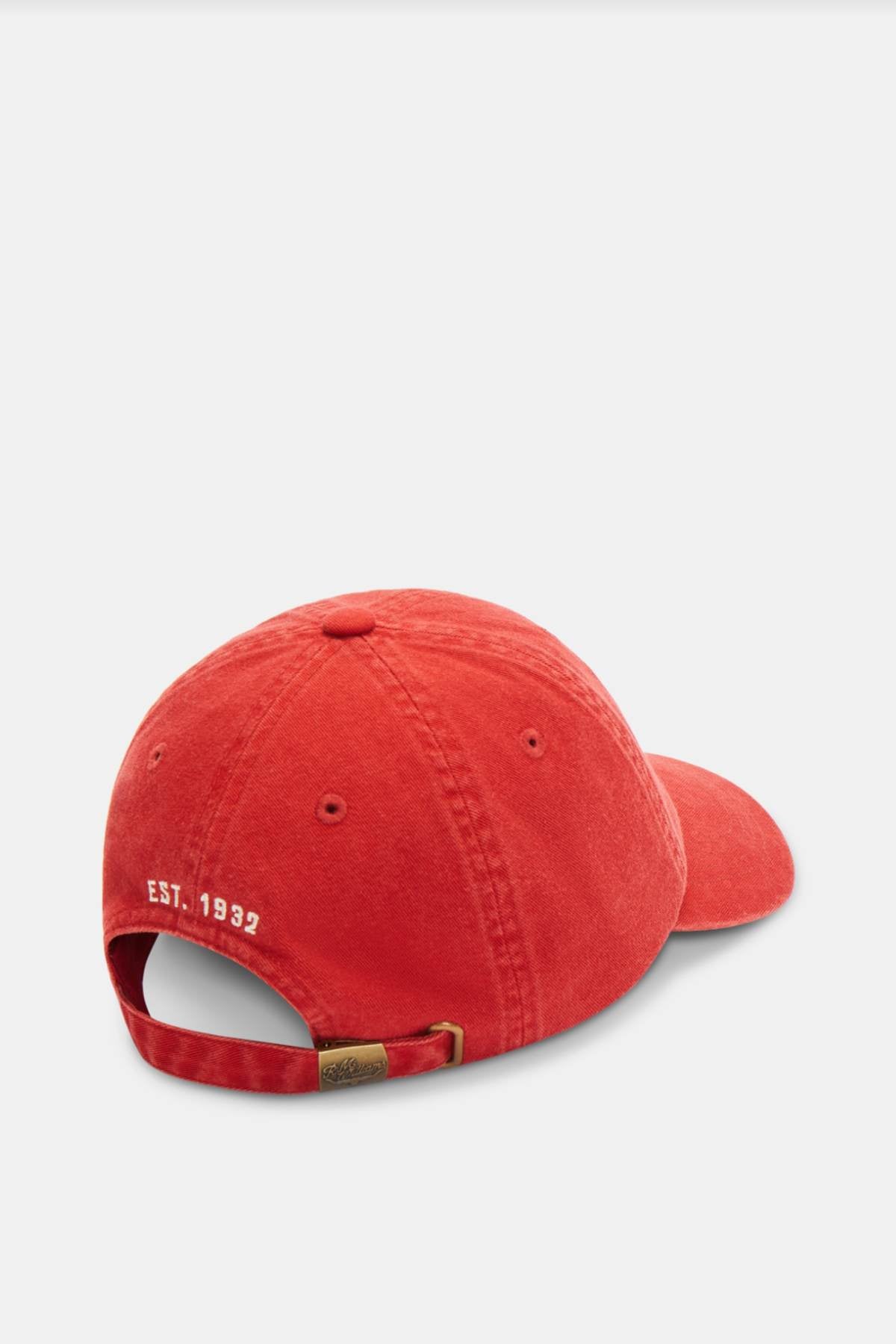 The RM Williams Script Longhorn Cap, made from washed cotton twill, features a red design with a curved brim and an adjustable strap at the back. The phrase "EST. 1992" is embroidered in white near the strap, offering a touch of subtle charm against its plain, light-colored background.