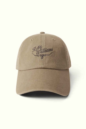 The RM Williams Script Longhorn Cap is a brown baseball cap made from washed cotton twill, featuring "R.M. Williams" embroidered in dark brown on the front above an illustration of longhorn cattle horns.