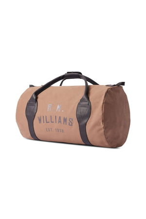 The RM Williams Sorrento Ute Bag is a tan canvas cylindrical duffel with black handles, leather trims, a top zipper closure, and "R.M. Williams Est. 1932" in gray on the side. Made in Australia.