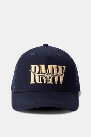 The RM Williams Steers Head Trucker Cap is navy blue with beige embroidery, showcasing the letters "RMW" and a longhorn skull design. It features an adjustable snapback and a mesh back for ventilation.