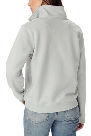 A person is seen from the back wearing a light gray RM Williams Trickett 1/4 Zip Sweatshirt and blue jeans, with their head turned slightly to the side.