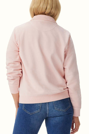 A person with blonde hair wearing an RM Williams Trickett 1/4 Zip Sweatshirt made of organic cotton and blue jeans is seen from the back, standing against a plain, light-colored background.