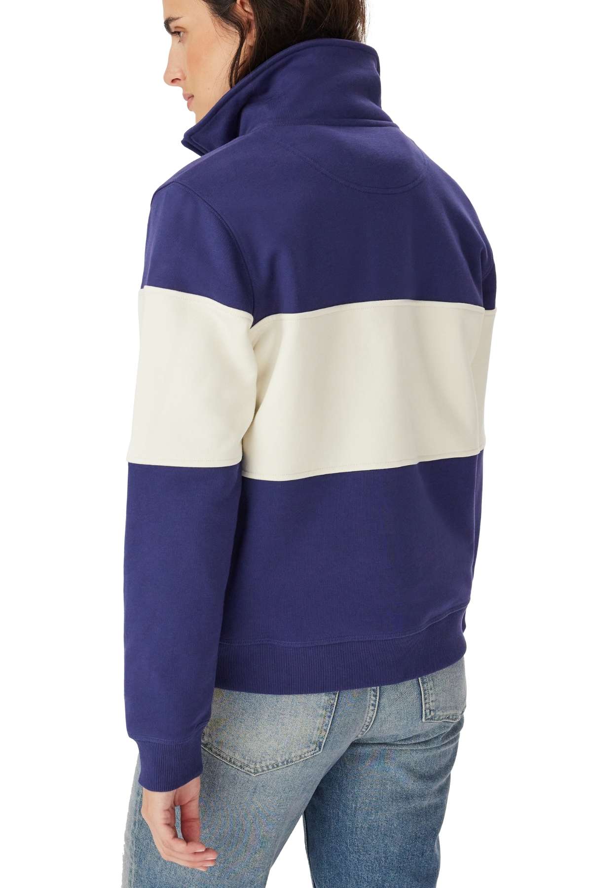 A person wearing the RM Williams Trickett Panel Sweatshirt in blue and white, featuring a wide white horizontal stripe across the back and arms, is shown from behind, looking to the side with light blue jeans.