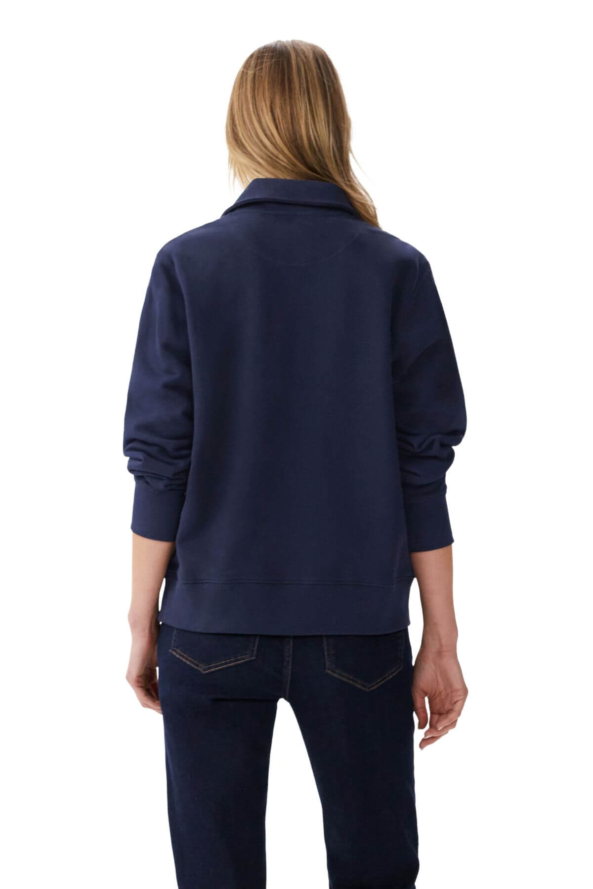 A person with long blonde hair, wearing the RM Williams Trickett Zip Neck Sweatshirt in navy blue and dark jeans, is shown from behind against a plain white background.