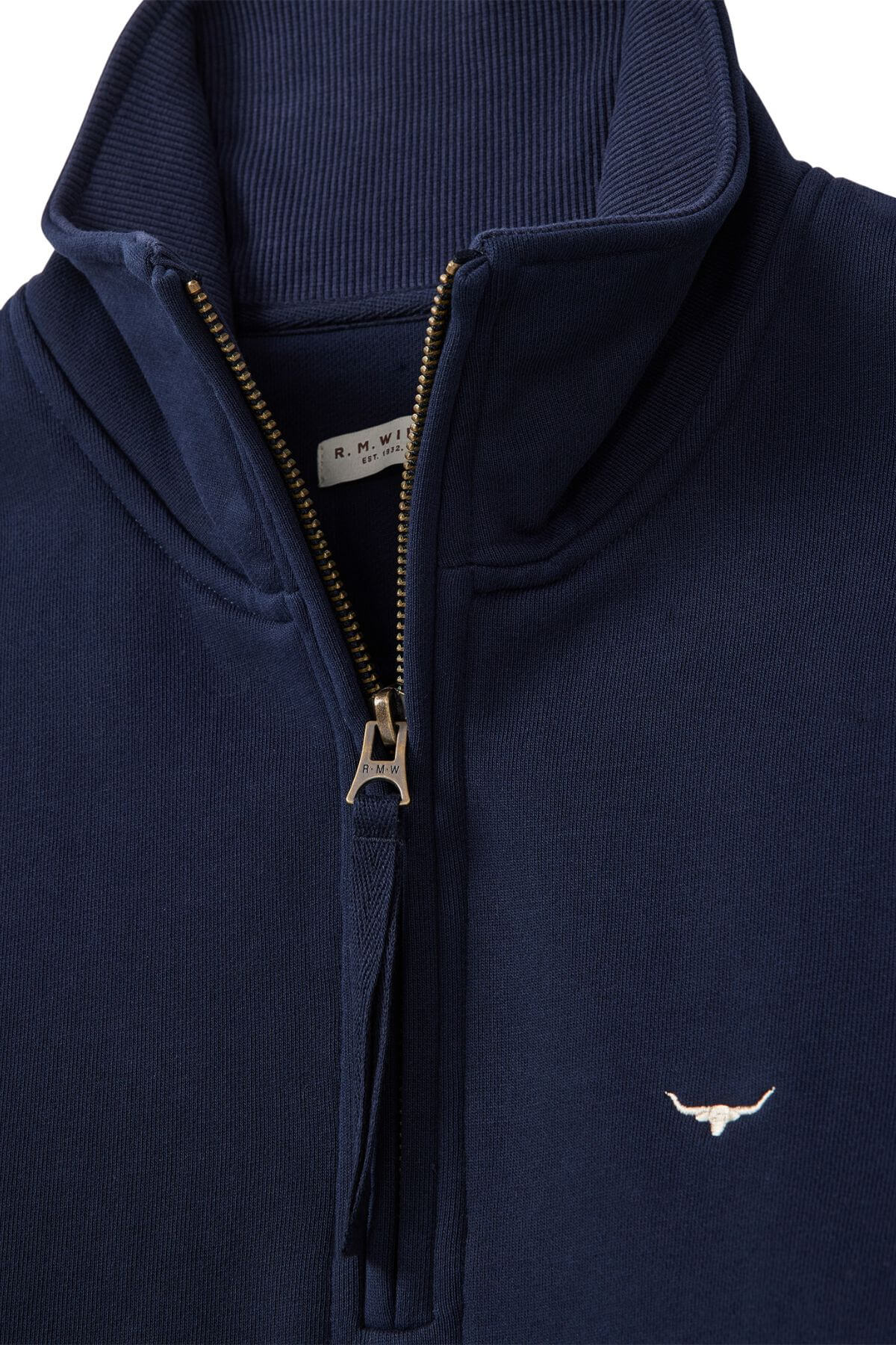 Close-up of the RM Williams Trickett Zip Neck Sweatshirt in navy Cotton Terry, with a silver zipper, Longhorn embroidery on the chest, and a visible "R.M. Williams" label inside the collar.
