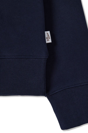 Close-up of the RM Williams Trickett Zip Neck Sweatshirt’s ribbed hem and cuff in navy blue cotton terry, featuring a small white fabric tag with cursive writing sewn into the seam.