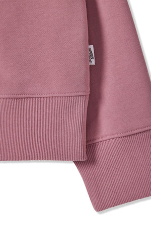 Close-up of the RM Williams Trickett Zip Neck Sweatshirt in pink, made from loop back cotton terry with ribbed cuffs and hem. A small white fabric tag with text is attached to the side, and the material appears soft and textured.