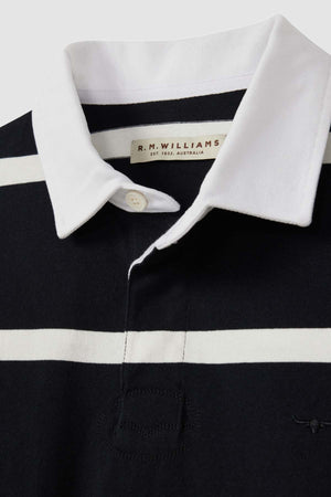 Close-up of the RM Williams Tweedale Rugby, a black and white striped polo shirt with a white collar and button, reminiscent of a classic rugby jersey. The label inside the collar reads "R.M. Williams Est. 1932 - Australia.