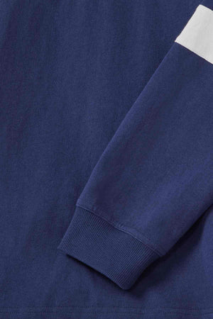 Close-up of the RM Williams Tweedale Rugby shirt in navy blue, showcasing its ribbed cuff at the wrist and a horizontal white stripe on the upper arm. The material looks comfortable with a slight texture, likely indicating cotton or a blend, and is adorned with subtle longhorn embroidery for an added touch of detail.