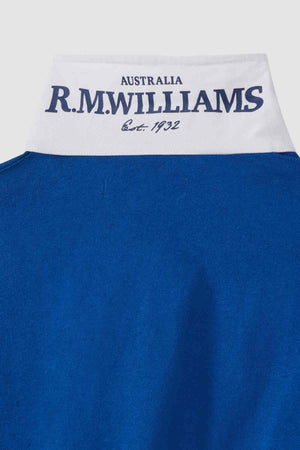 Close-up of the collar of the RM Williams Tweedale Rugby shirt, featuring a blue exterior with a white inside. The inner collar has "AUSTRALIA R.M. WILLIAMS Est. 1932" printed in dark blue text. The rest of the image prominently displays the heavyweight blue jersey fabric of the garment.