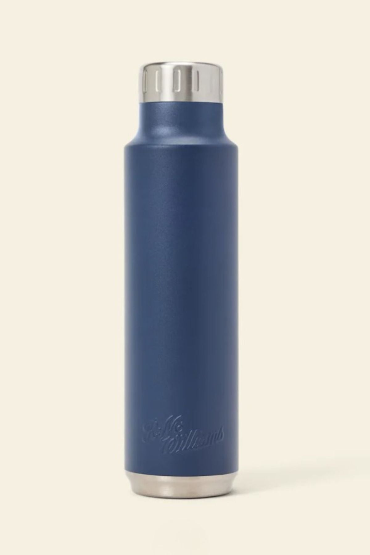 The RM Williams Water Bottle is a tall, navy blue stainless-steel vacuum flask with a silver screw-top lid and base, shown upright on a beige background. Subtle logo engraving near the bottom keeps your drink perfectly hot or cold on any adventure.
