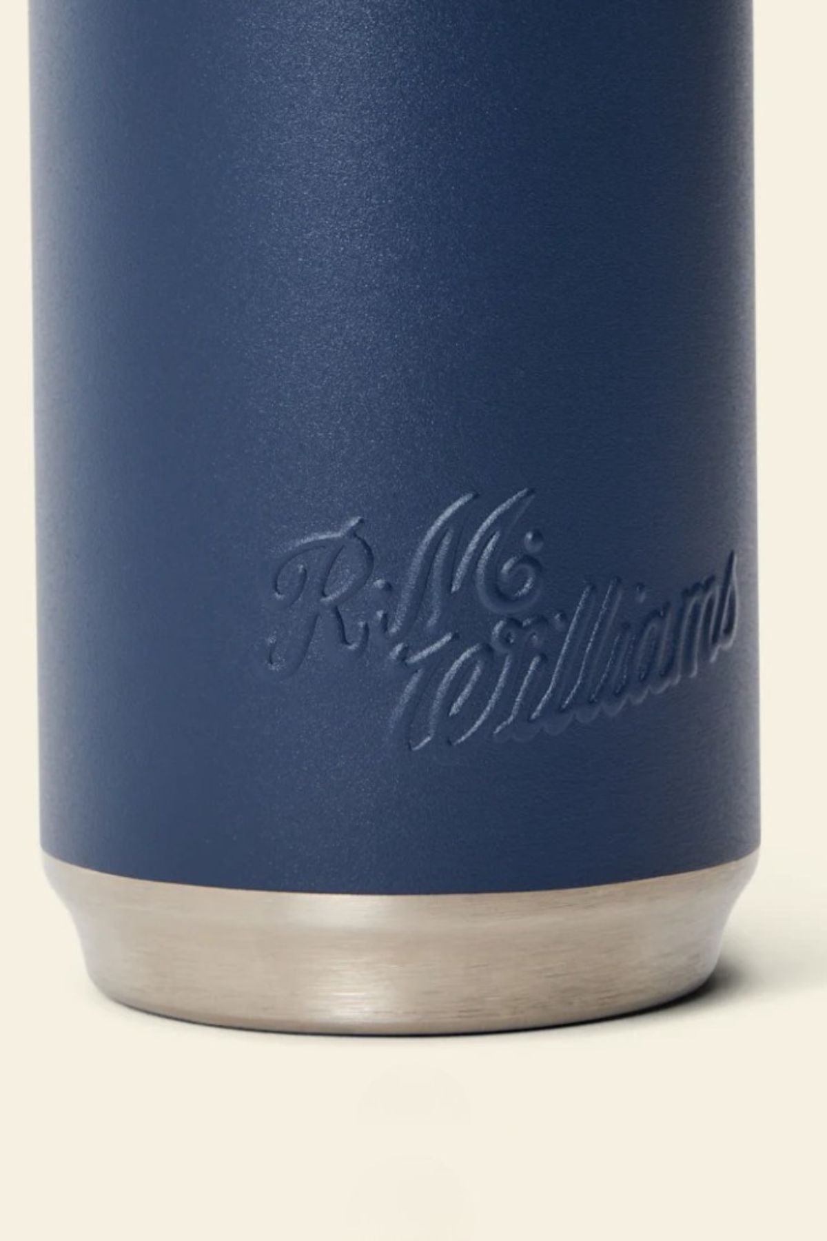 A close-up of the RM Williams Water Bottle in navy blue, embossed with "R.M. Williams" in cursive and finished with a silver stainless steel base—a stylish, temperature-retaining choice for any adventure pack.