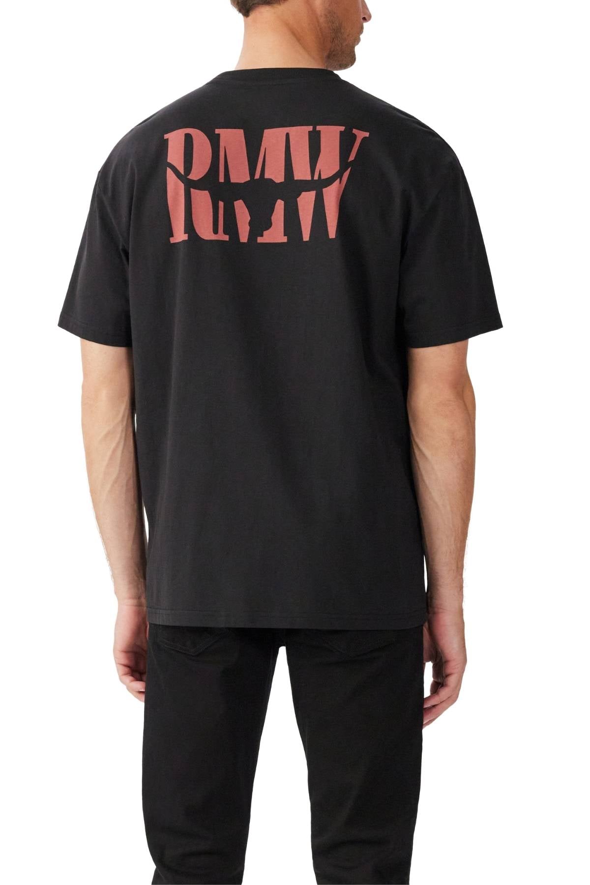 A man stands with his back to the camera, wearing a relaxed fit RM Williams Branded T-Shirt in black with bold red "RMV" lettering on the back and black pants, highlighting casual style in organic cotton jersey against a white background.