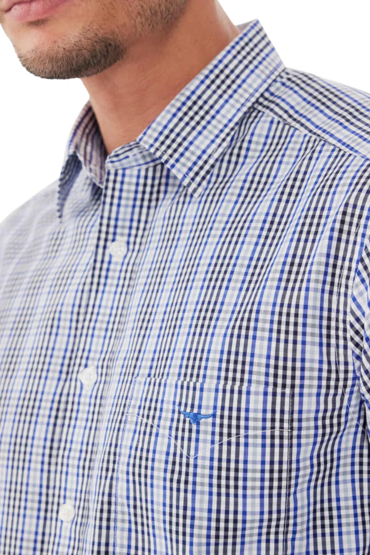Close-up of a person wearing the RM Williams Collins Shirt, a blue and white checked twill cotton button-down. The shirt showcases a small embroidered longhorn emblem on the pocket, with only the lower face and neck visible to emphasize its intricate details.