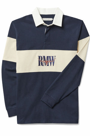 The RM Williams Heritage Rugby is a navy blue and cream long-sleeve shirt made from organic heavyweight brushed cotton, featuring a white collar, bold cream chest stripe, and an embroidered "RMW" Heritage logo on the front.