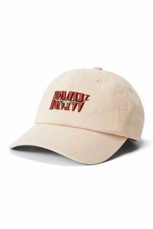 The RM Williams Heritage Twill Cap is a beige organic cotton cap with a curved brim, featuring “DAMN! LUCKY” and a horseshoe embroidered on the front, plus an adjustable strap for a comfortable fit.