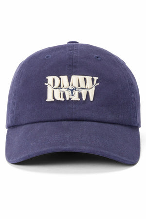 The RM Williams Heritage Twill Cap is a navy blue organic cotton cap with "PMW" and an airplane embroidered in white on the front. It features an adjustable strap for a comfortable fit.