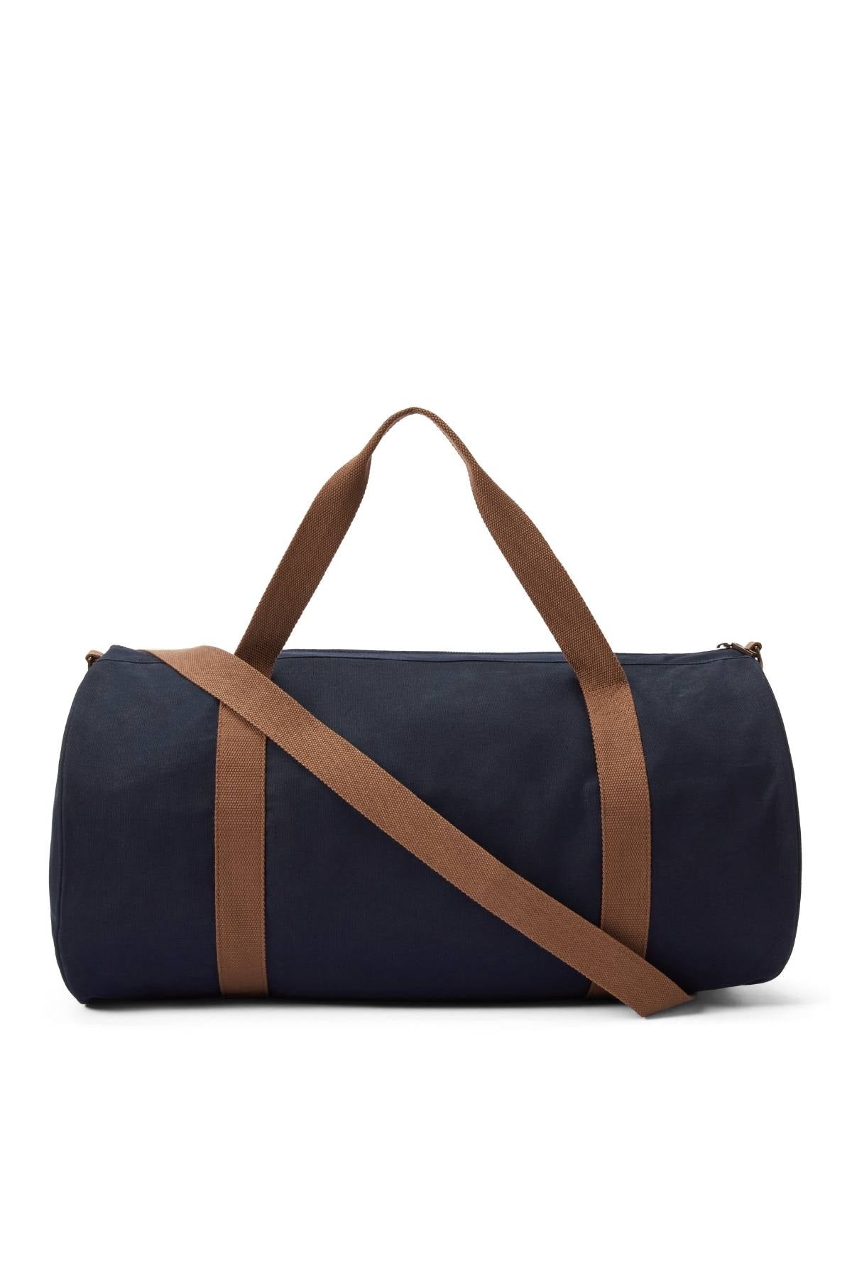 The RM Williams Heritage Bag is a cylindrical navy blue cotton canvas bag with brown shoulder and hand straps, plus an adjustable crossbody strap for versatile carrying. Shown against a white background.