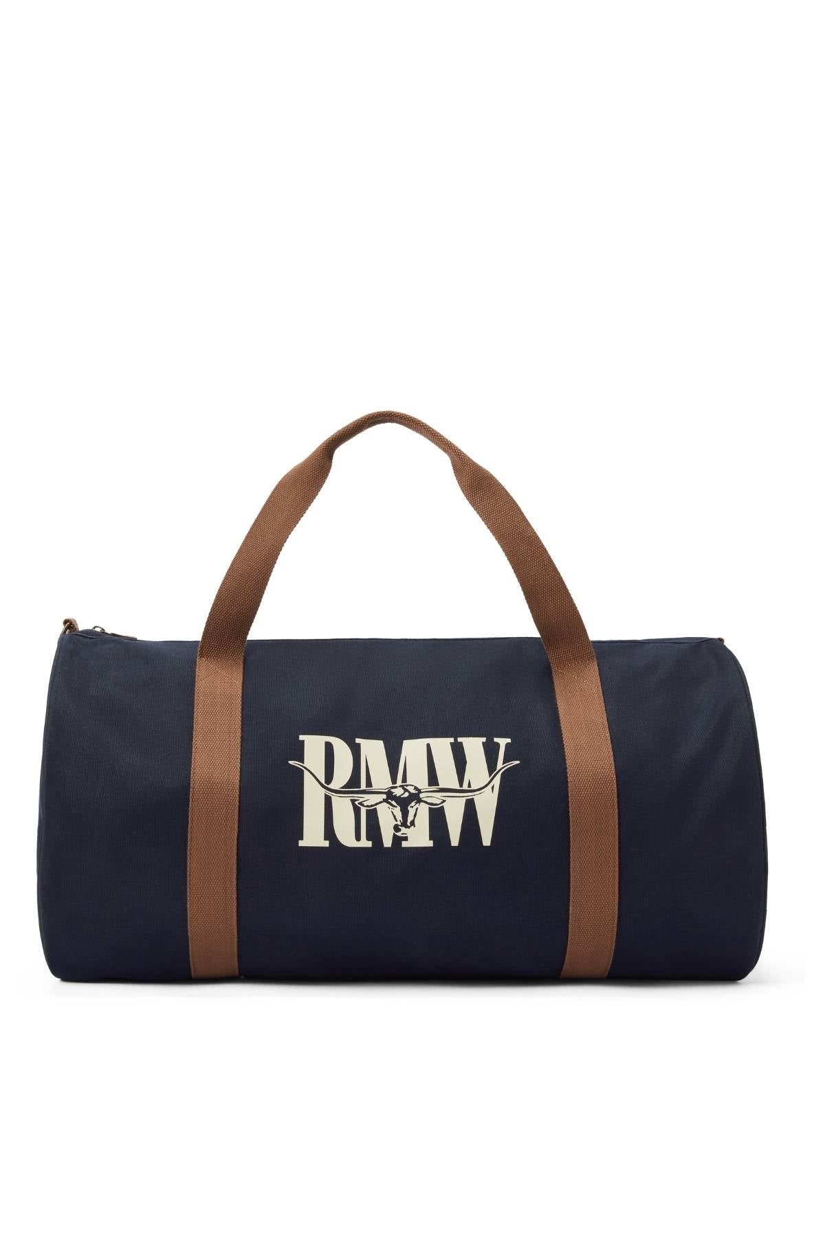 The RM Williams Heritage Bag is a navy blue cotton canvas bag with brown handles, a zipper, and bold white "RMWW" heritage logo on the front.