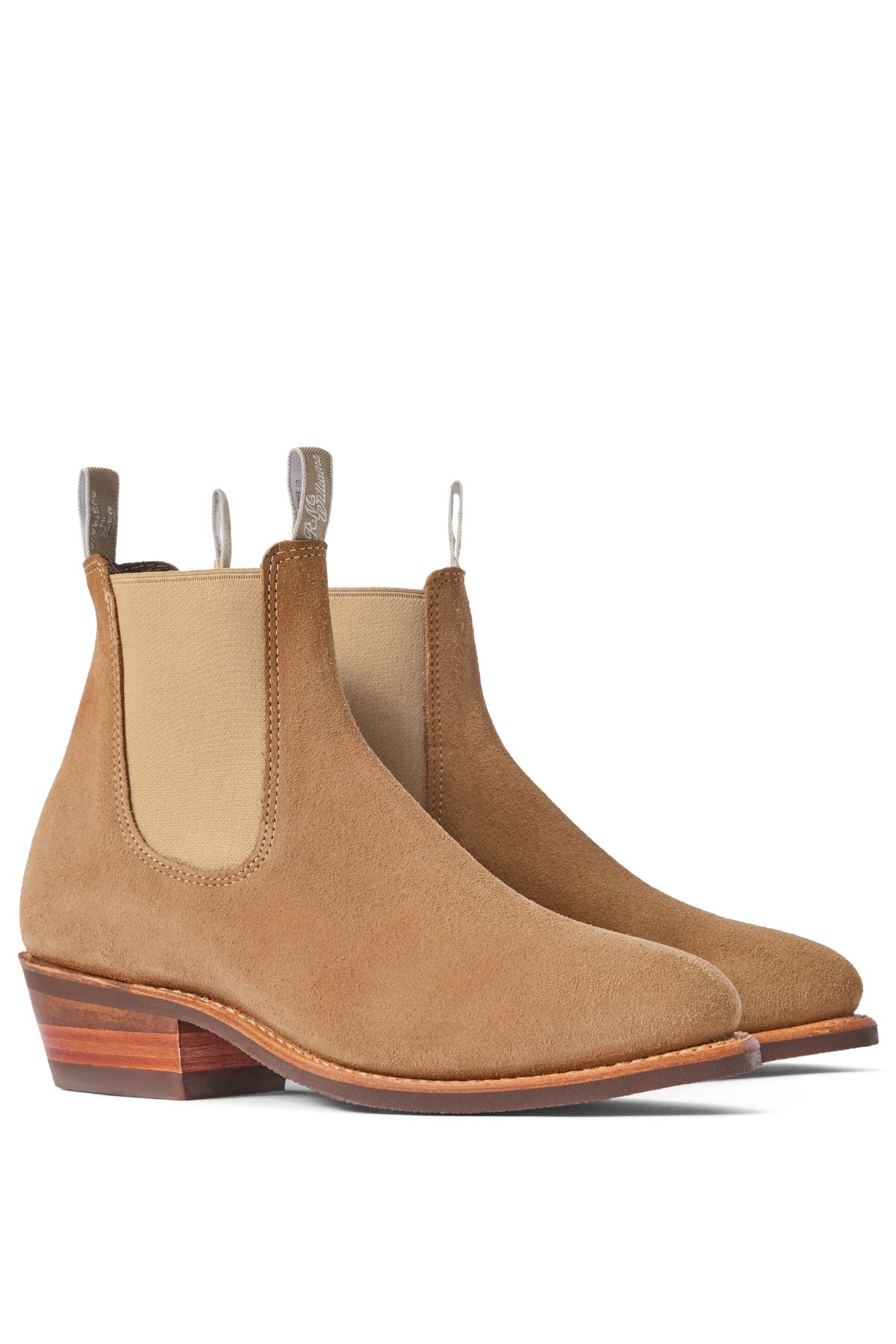 The RM Williams Comfort Lady Yearling Suede Rubber Sole Boot is a women's tan Italian suede Chelsea boot with elastic side panels, pull tabs, and stacked wooden heels, shown on a white background.