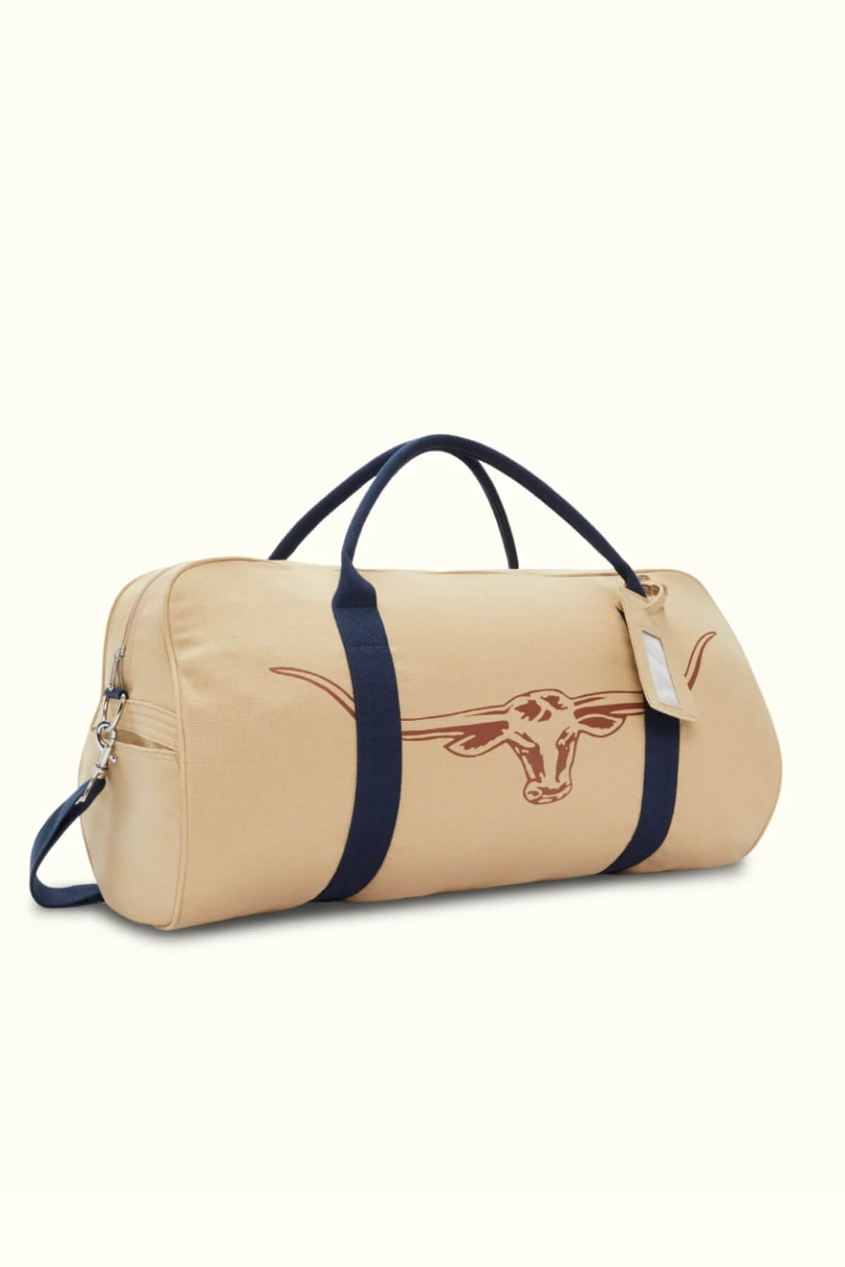 The RMW Nanga Canvas Bag is a beige duffel-style bag with dark blue straps and a longhorn symbol on the side. This versatile bag has a side zipper and includes a small luggage tag.