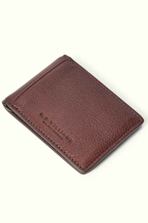 The RM Williams Farrier Bi Fold Wallet, crafted from brown premium leather with visible stitching and embossed with "R.M. WILLIAMS" on the front, features a modern closed design that stands out against a plain white backdrop.