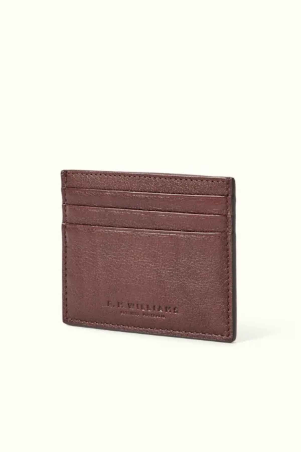 The RM Williams Farrier Card Holder, crafted from premium leather and featuring multiple card slots, elegantly displays the embossed brand name on the front against a simple light backdrop.