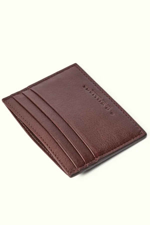 This RM Williams Farrier Card Holder, made from premium brown leather, features a simple and sleek design with four visible card slots. The prominent stitching along the edges adds to its elegance as it sits at an angle on a light background.