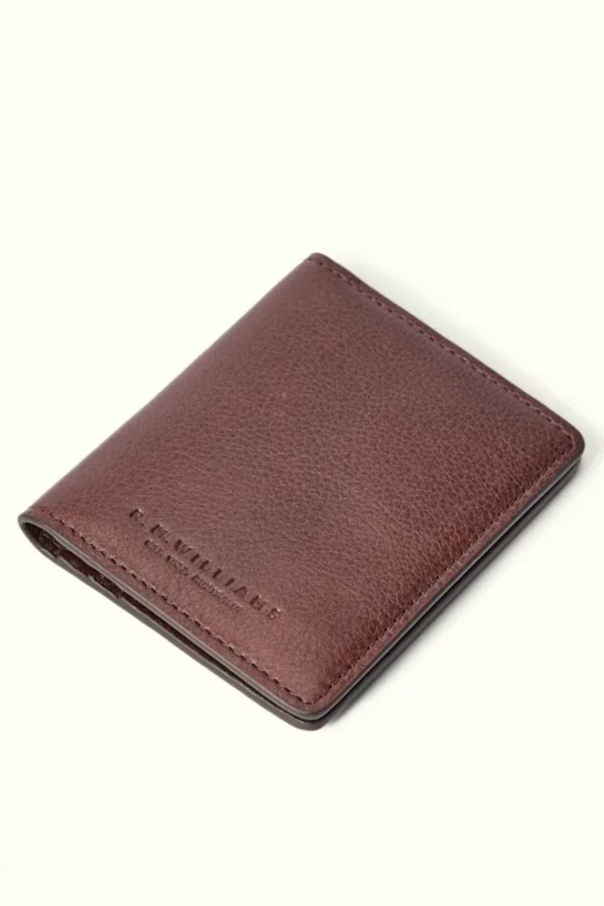 The RM Williams Farrier Fold Cardholder is crafted from premium brown leather, showcasing visible stitching and an embossed "R.M. Williams" logo in the bottom corner. It includes card slots for organization and is elegantly displayed against a plain light background, exuding understated luxury.