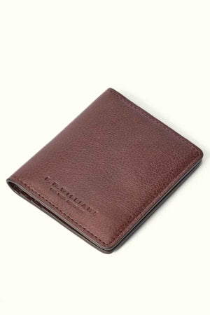 The RM Williams Farrier Fold Cardholder is crafted from premium brown leather, showcasing visible stitching and an embossed "R.M. Williams" logo in the bottom corner. It includes card slots for organization and is elegantly displayed against a plain light background, exuding understated luxury.