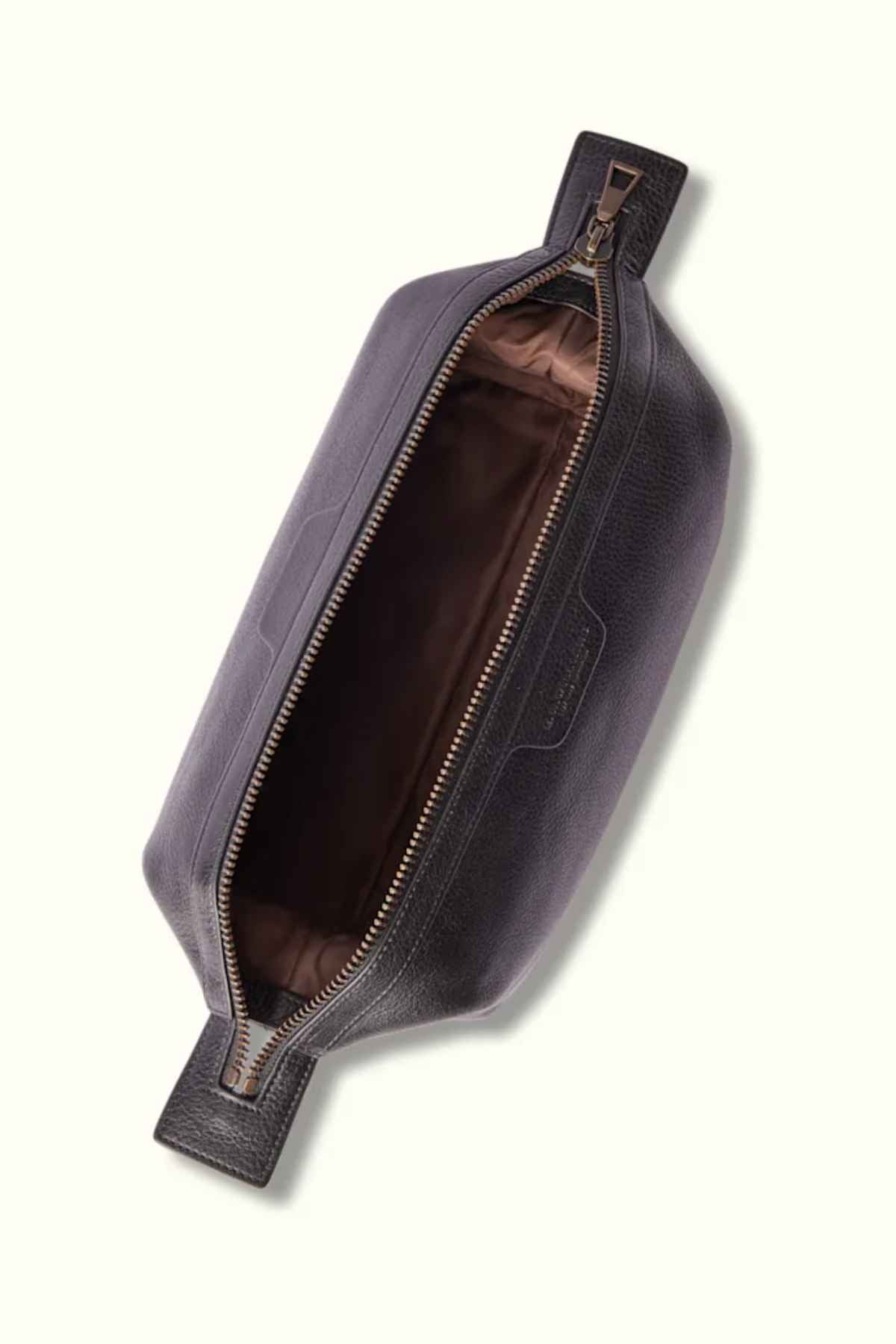 A top-down view of the RM Williams Farrier Washbag reveals its open, rectangular shape crafted from dark leather with a visible brown fabric interior. The partially opened frog-mouth zipper showcases its spacious inside, highlighting the washbag's sleek and minimalist design.
