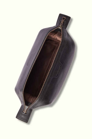 A top-down view of the RM Williams Farrier Washbag reveals its open, rectangular shape crafted from dark leather with a visible brown fabric interior. The partially opened frog-mouth zipper showcases its spacious inside, highlighting the washbag's sleek and minimalist design.