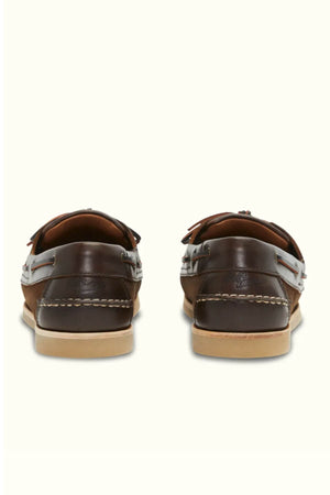 The RM Williams Hobart Boat Shoe is made of brown bovine leather with white stitching, tan rubber soles, and lace details around the sides. Shown from the back against a plain light background.