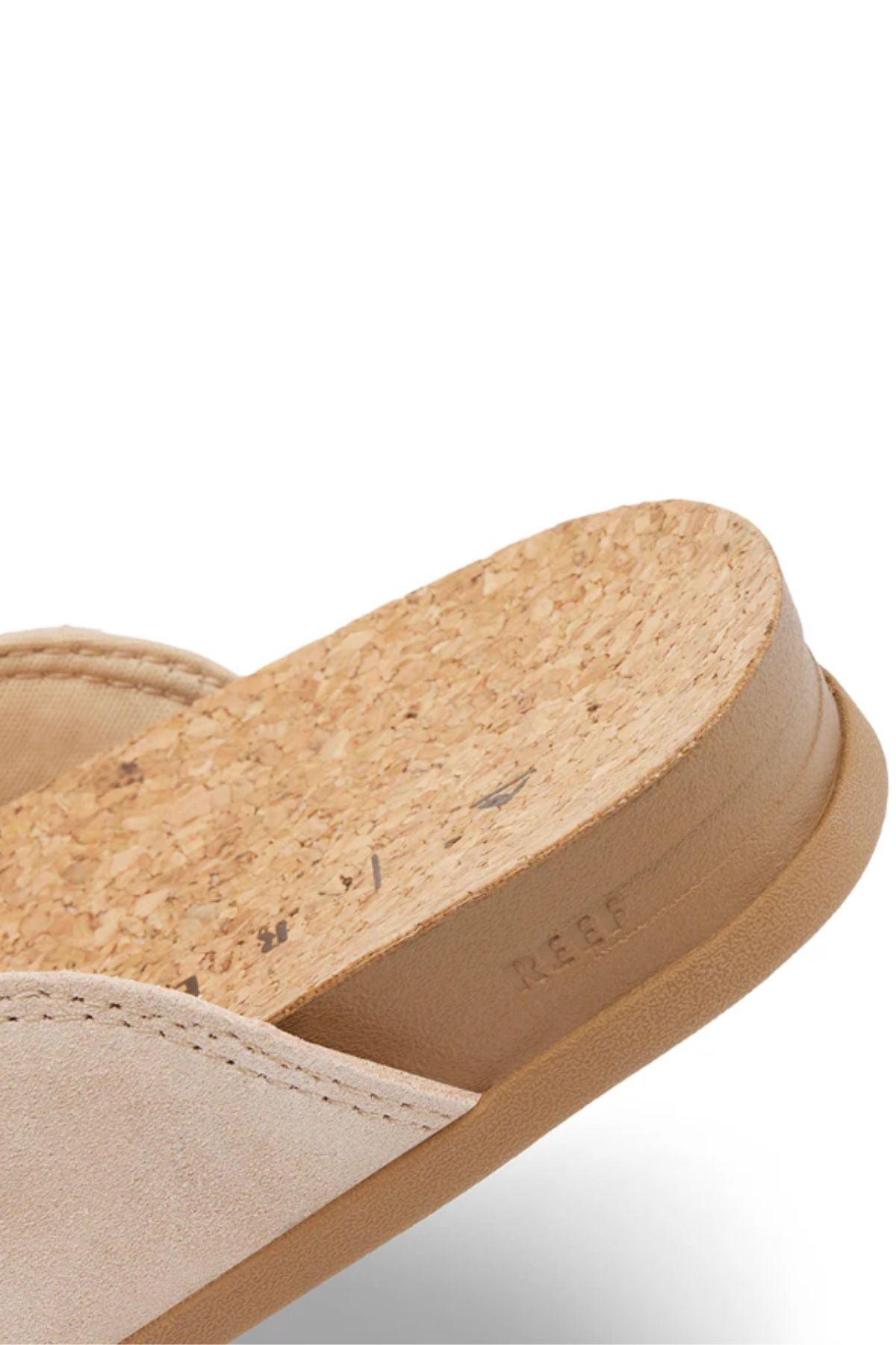 Close-up of the REEF Vista Serenity sandal, featuring a cork footbed, suede upper, and light brown rubber sole. The comfortable women's sandal has "REEF" subtly embossed on the side of the sole.