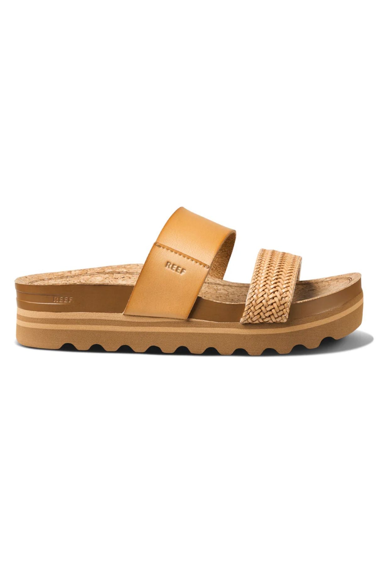 The REEF Cushion Vista Hi TX is a tan platform sandal with a wide leather strap, woven detail, cushioned midsole, cork footbed, and ridged rubber sole—stylish and sustainable for everyday wear. "Reef" logo featured on strap and footbed.