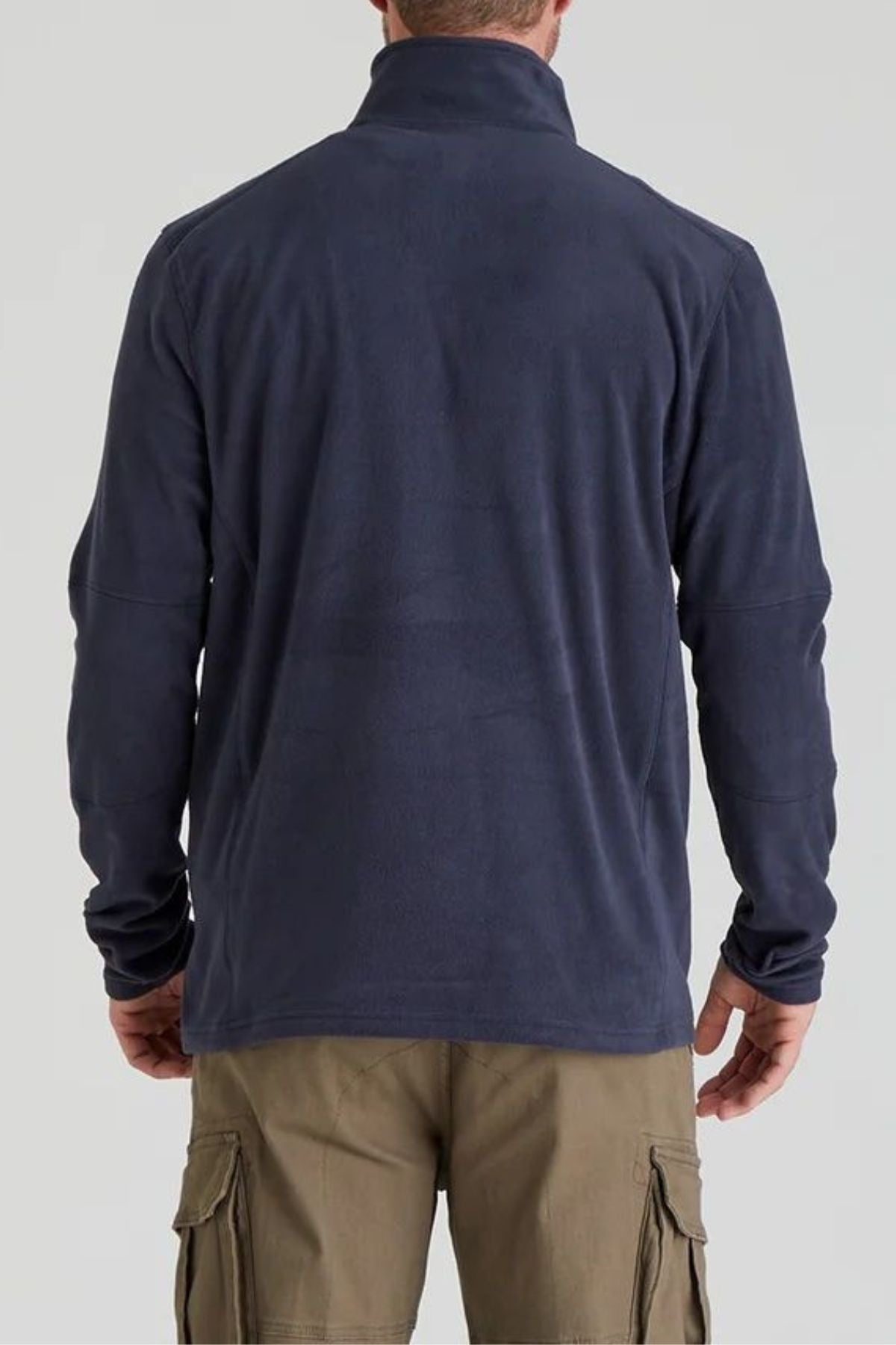 A person stands with their back to the camera, wearing the Ridgeline Narvik Fleece in navy blue and light brown cargo pants, set against a plain gray background.