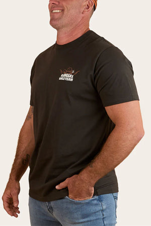 A man smiling and looking to the side wears a black Ringers Western Country Club Loose Fit T-Shirt with a small chest logo and light blue jeans.