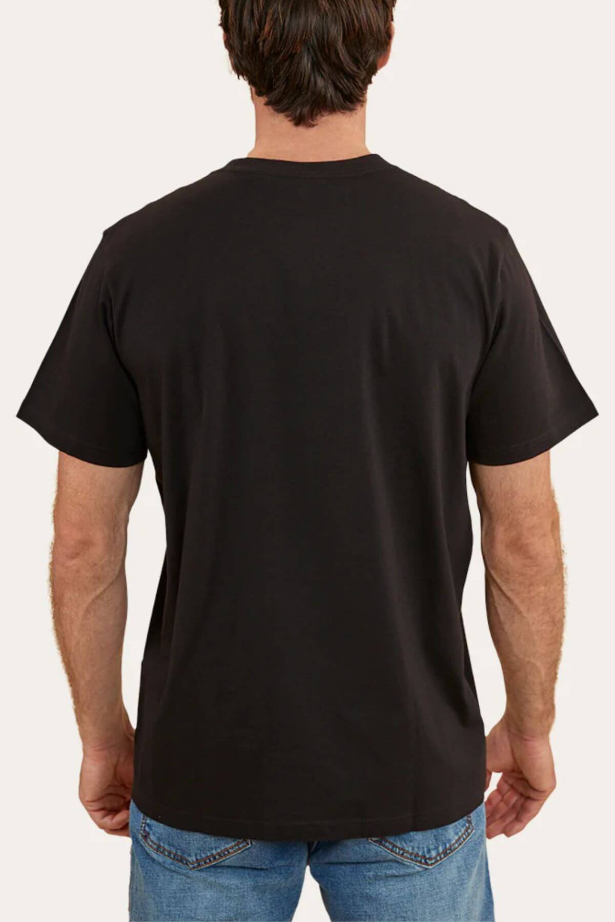 A person with short dark hair is seen from the back, wearing a Ringers Western Hastings Loose Fit T-Shirt made of 100% cotton jersey in plain black, paired with blue jeans. The background is a plain light color.