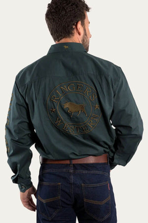 A man is wearing the Ringers Western Hawkeye Embroidered Shirt in dark green premium cotton, featuring "Ringers Western" and a bull logo on the back and left sleeve. His look is completed with dark jeans and a brown belt, viewed from behind.