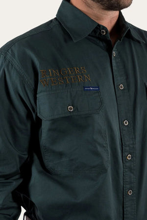 A person wears a Ringers Western Hawkeye Embroidered Shirt in dark green premium cotton, with "RINGERS WESTERN" on the chest and two pockets, one showing a logo tag. They face slightly to the right.
