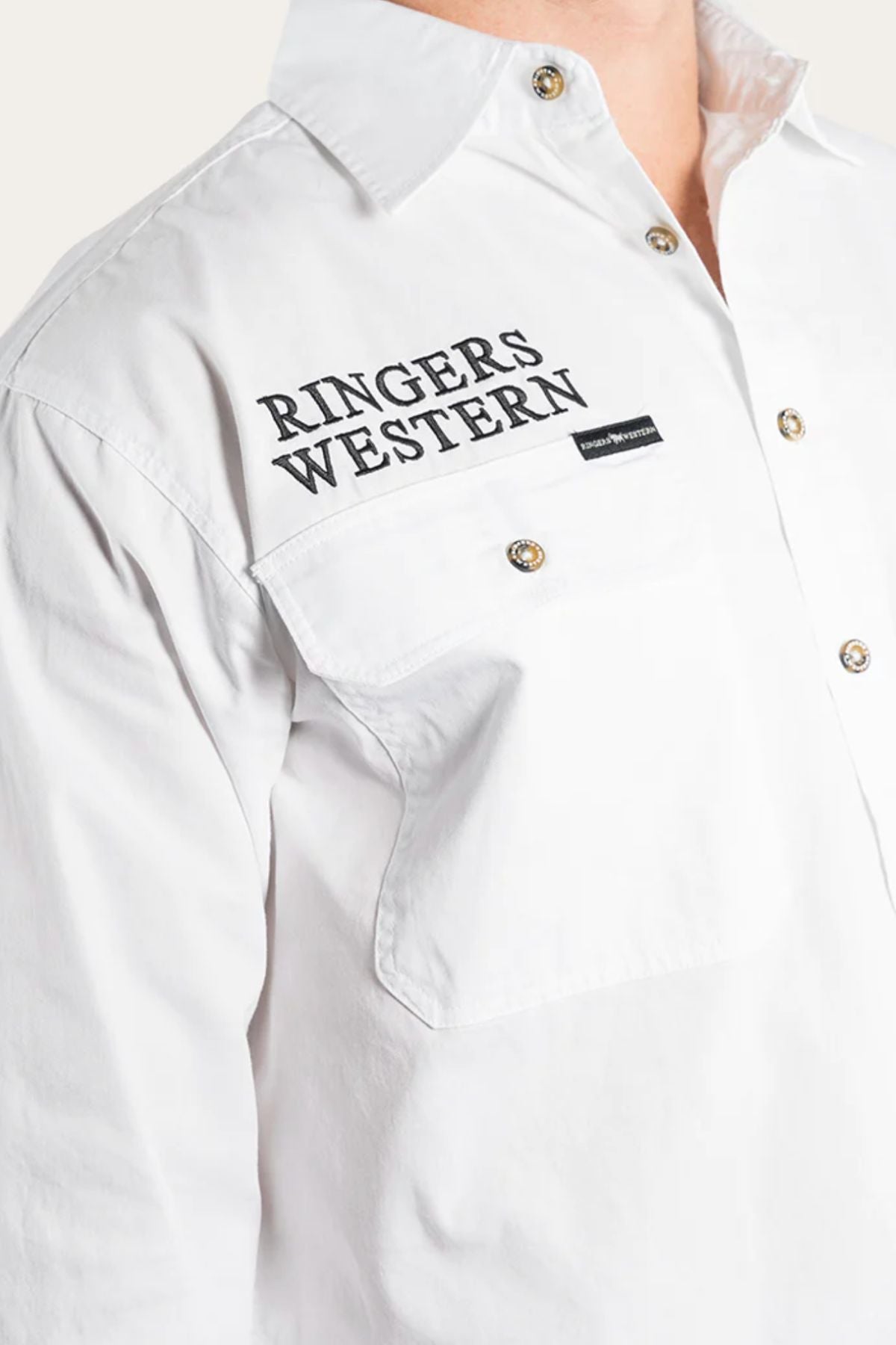 Wearing the Ringers Western Hawkeye Embroidered Shirt, a white premium cotton button-up featuring "RINGERS WESTERN" printed in black on the chest, metal buttons, a small black tag below, and a classic collar.