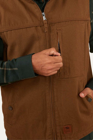 A person wearing the Ringers Western High Country Vest over a dark green shirt is unzipping a vertical chest pocket on the vest. Only their torso and hand are visible.