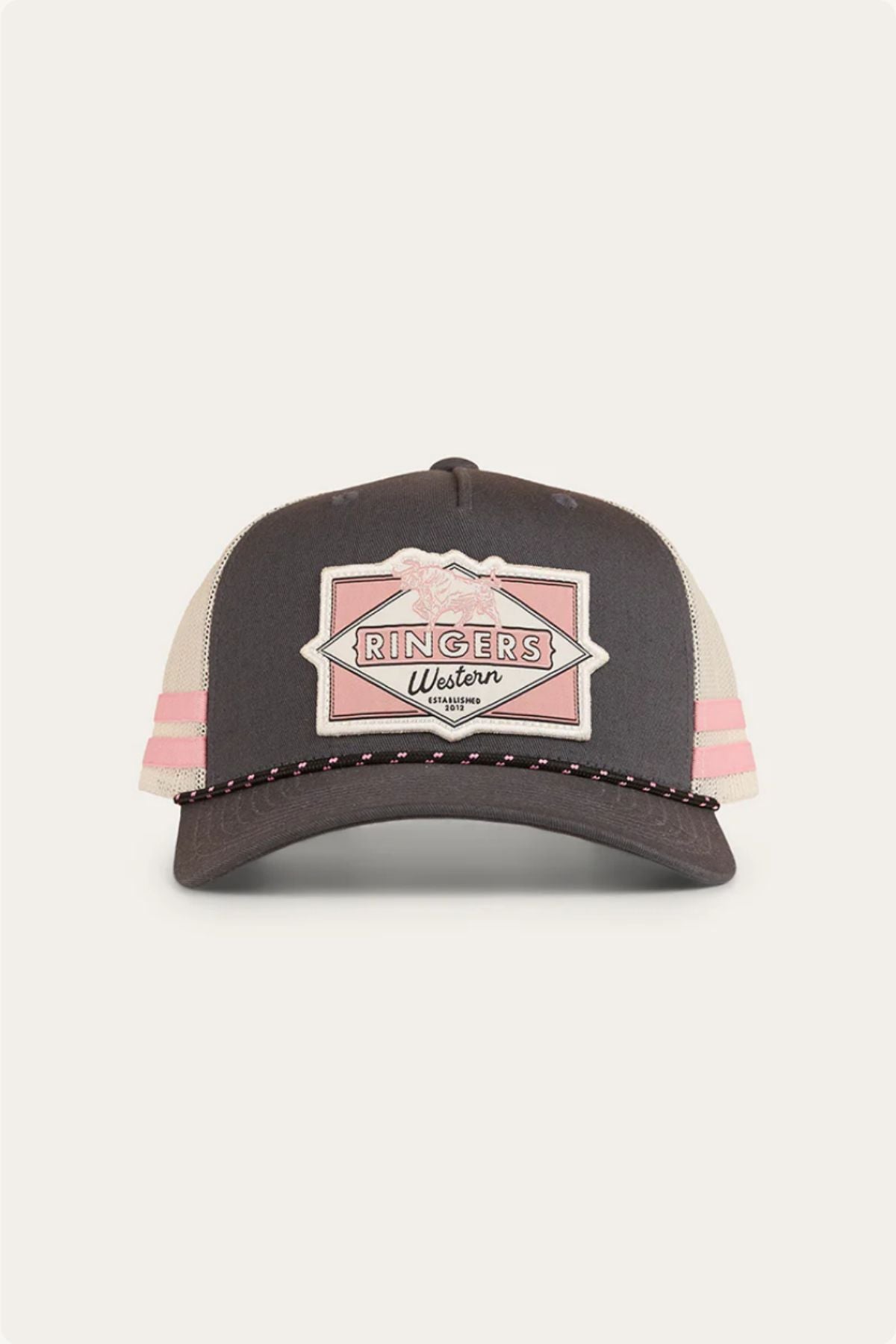 Front view of the Ringers Western Hometown Trucker Cap featuring a dark front, beige mesh sides, pink stripes, a stitched "RINGERS Western" patch, pink and white stitching on the brim, and an adjustable snapback for a custom fit.