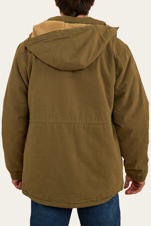 A person with short dark hair is seen from the back, wearing a brown Ringers Western Judd Jacket with a fur sherpa lining on the hood. The jacket has a relaxed fit and features a removable hood. They are also wearing blue jeans, with a neutral background adding to the simplicity of the scene.