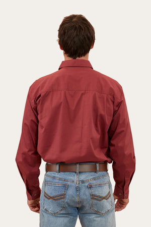 A person with short dark hair is shown from the back, wearing a long-sleeved Ringers Western King River Half Button Shirt tucked into blue jeans. The individual is standing against a plain light background.